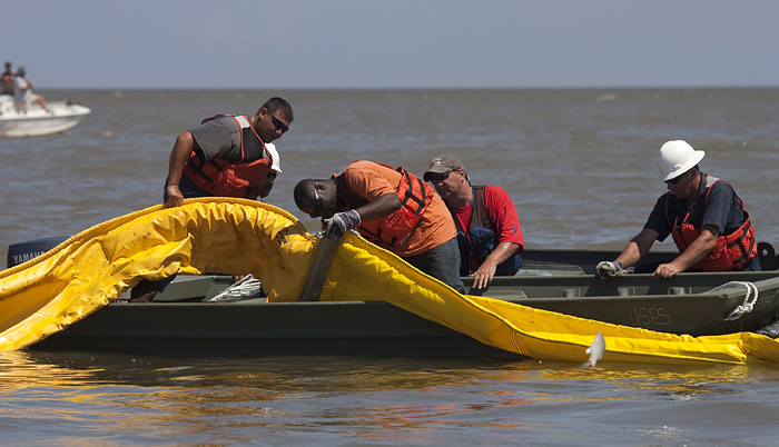 A fish jumps near workers laying protective oil booms near Pass a Loutre, Louisiana May 20, 2010. For nearly a month, roughly 5,000 barrels (210,000 gallons/795,000 liters) of oil per day have been gushing from BP's broken Deepwater oil well situated in the Gulf of Mexico, in what could be named the worst oil spill in U.S. history. REUTERS/Lee Celano (UNITED STATES - Tags: DISASTER ENVIRONMENT)