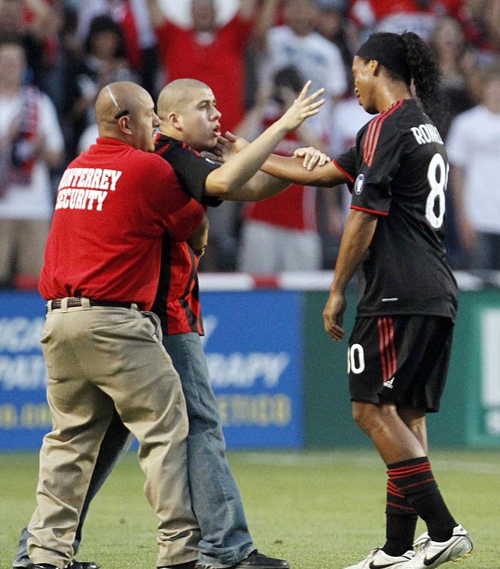 A fan, center, talks to A.C. Milan's Ronaldinho as security guard tries to catch during the first half of an international friendly soccer match between A.C. Milan and the Chicago Fire in Bridgeview, Ill., Sunday, May 30, 2010. (AP Photo/Nam Y. Huh)