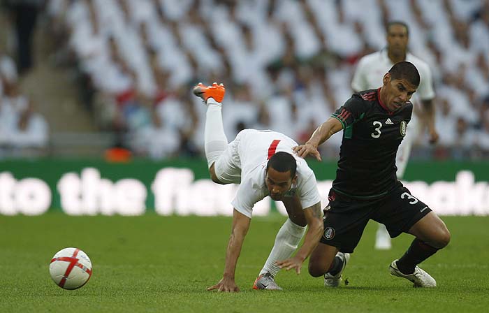 England's Theo Walcott, left, is tackled by Mexico's Carlos Salcido during their international soccer friendly match at Wembley stadium in London, Monday, May 24, 2010. Both England and Mexico have qualified for the World Cup in South Africa 2010, and are playing a series of friendlies in preparation for the competition. (AP Photo/Lefteris Pitarakis)