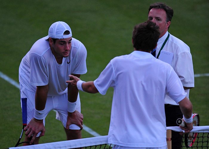 France's Nicolas Mahut (C) speaks with officials, watched by John Isner of the US (L), just before their match is suspended due to poor light, on the third day of during the Wimbledon Tennis Championships at the All England Tennis Club, in southwest London, on June 23, 2010. Tennis history was made at Wimbledon on Wednesday as France's Nicolas Mahut and John Isner of the United States shattered the record for the longest-ever match.    AFP PHOTO / ADRIAN DENNIS