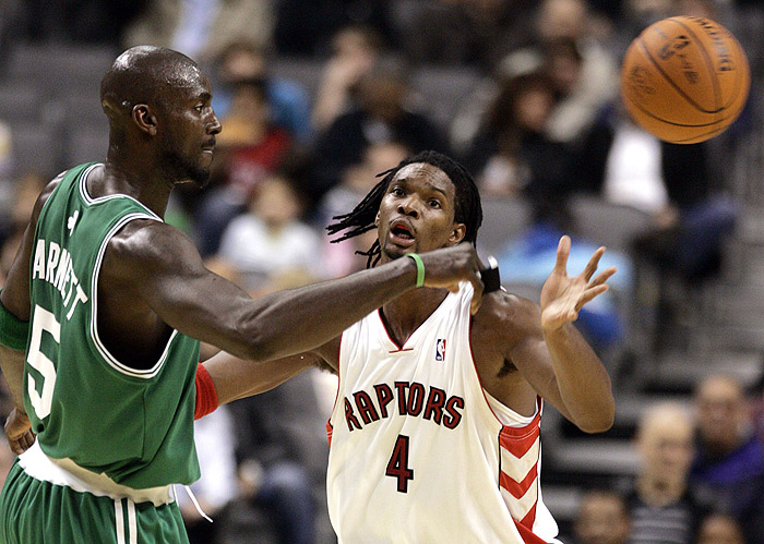 Boston Celtics forward Kevin Garnett (L) passes the ball against Toronto Raptors forward Chris Bosh during the first half of their pre-season NBA basketball game in Toronto October 18, 2009.   REUTERS/ Mike Cassese   (CANADA SPORT BASKETBALL)