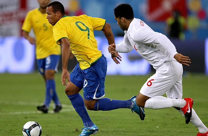 England's Joleon Lescott (R) runs to intercept Brazil's Luis Fabiano as he advances with the ball during their friendly football match at the Khalifa Stadium in the Qatari capital Doha on November 14, 2009. AFP PHOTO/MARWAN NAAMANI