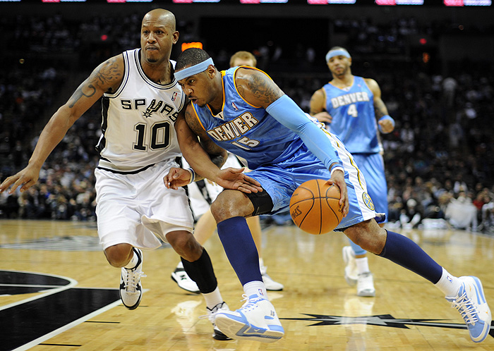 Denver Nuggets forward Carmelo Anthony, right, drives against the San Antonio Spurs' Keith Bogans during the first half of an NBA basketball game at the AT&T Center in San Antonio, Saturday, Dec. 5, 2009. (AP Photo/ Bahram Mark Sobhani)