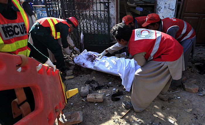 Rescue workers carry the body of a dead man at the site of a suicide bomb attack at the gate of the Press club in Peshawar, located in Pakistan's North West Frontier Province, December 22, 2009. A suicide bomber blew himself up on Tuesday at the gate of the Press club in the northwestern city of Peshawar, killing three people and wounding 17, government officials said. REUTERS/Fayaz Aziz     (PAKISTAN - Tags: CIVIL UNREST CRIME LAW CONFLICT)