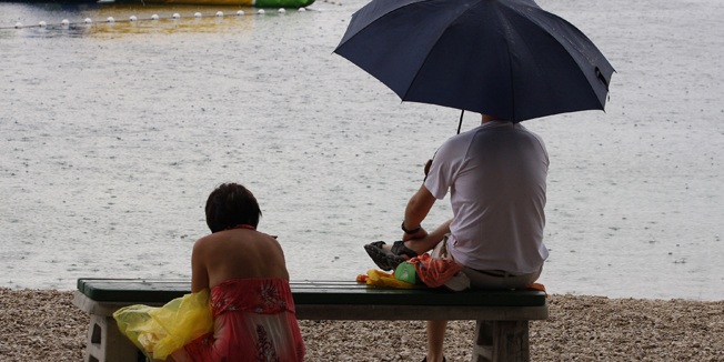 Makarska, 080714.Prolazak ciklone Iskra koja je donijela oblake i kisu ispraznio je makarske plaze. Usprkos tome sto su temperature mora izraka ostale ugodne tek se rijetki odlucuju na kupanje po kisi.Na fotografiji: Rijetki turisti na makarskoj plazi.Foto: Ivo Ravlic / CROPIX