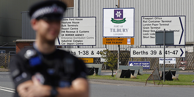 A policeman stands guard outside the entrance to Tilbury Docks, east of London on August 16, 2014, where one man was found dead and 19 people, including seven children, were taken to hospital on Saturday after they were discovered inside a shipping container at the British port. Some 31 people, the dead man included, were found inside the container which had arrived on a ship from the Belgian port of Zebrugge and was being unloaded by the Port of Tilbury authorities. AFP PHOTO / CYRIL VILLEMAIN