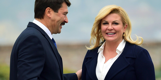 Hungarian President Janos Ader and his Croatian counterpart Kolinda Grabar-Kitarovic share a smile during an official welcoming ceremony in front of the presidential palace of Buda Castle in Budapest on October 7, 2015. Kolinda Grabar-Kitarovic is on a two-day official visit to Hungary and will meet with her counterparts of Visegrads countries (Czech Republic, Hungary, Poland ans Slovakia).  AFP PHOTO / ATTILA KISBENEDEK