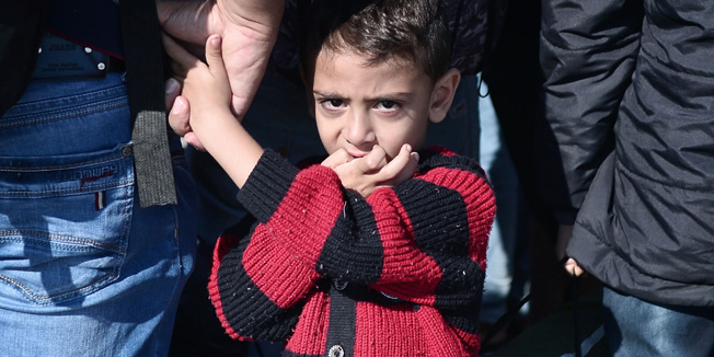 A migrant boy looks on as refugees and migrants disembark from a ferry which arrived from Lesbos island in the port of Piraeus on October 6, 2015.  Some 7000 migrants and refugees are expected to arrive to the port of Piraeus on October 6, on chartered or line ferries, according to Greek media. Over half a million migrants have crossed the Mediterranean to Europe this year, over 400,000 of whom have landed in Greece.  AFP PHOTO / LOUISA GOULIAMAKI