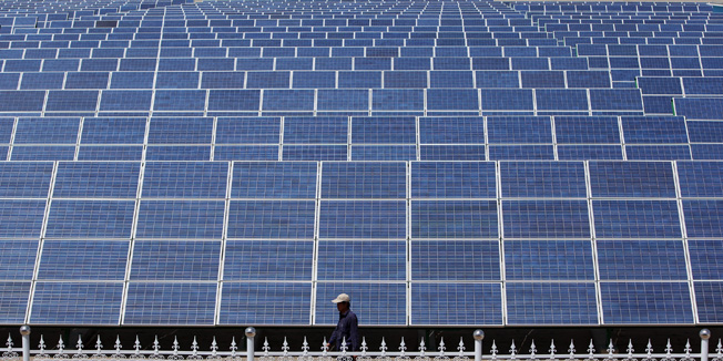 DUNHUANG, GANSU - JULY 21:  A Chinese worker walks near the solar modules of a newly installed 100MW photovoltaic on-grid power project on July 21, 2010 in Dunhuang of China's northwest Gansu Province. The government is tendering for bids to develop 13 solar projects with a combined capacity of 280MW in the western regions. The Chinese government has set a target to install 20GW of solar energy capacity and 100GW of wind power by 2020.  (Photo by Feng Li/Getty Images)