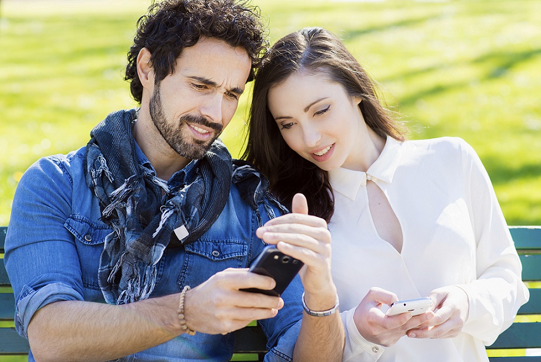 Smiling man showing his mobile phone to a girl