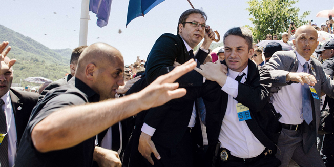 Bodyguards try to protect Serbian Prime Minister Aleksandar Vucic (C) from stones hurled at him by an angry crowd at the Potocari Memorial Center, near the eastern Bosnian town of Srebrenica on July 11, 2015. Tens of thousands of people gathered in Srebrenica on July 11 to commemorate the 20th anniversary of the massacre of thousands of Muslims in the worst mass killing in Europe since World War II. Serbian Prime Minister Aleksandar Vucic was forced to leave the Srebrenica memorial when the crowd started to chant 'Allahu Akbar' (God is Great) and to throw stones. AFP PHOTO / DIMITAR DILKOFF
