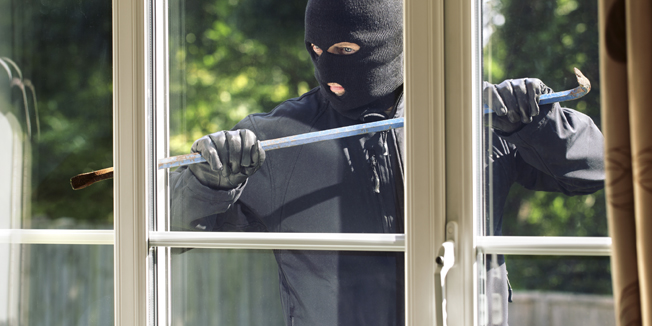 Burglar breaking into a house via a window with a crowbar