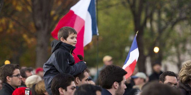 A young boy looks on near a French flag during a vigil to show solidarity with the citizens of France on November 14, 2015 in Washington, DC, a day after the Paris terrorist attacks. Islamic State jihadists claimed a series of coordinated attacks by gunmen and suicide bombers in Paris on November 13 that killed at least 129 people in scenes of carnage at a concert hall, restaurants and the national stadium. AFP PHOTO/ANDREW CABALLERO-REYNOLDS