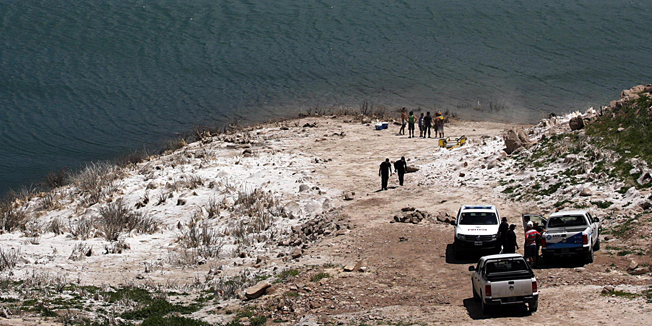 Photo released by Telam of policemen standing on the banks of an artificial lake in the Mendoza river, where a helicopter carrying two members of a team recording for a reality show of US MTV sunk after exploding in Potrerillos, some 30 km southeast of Mendoza, Argentina on December 12, 2015. Both occupants were killed. AFP PHOTO / TELAM / ALFREDO PONCE