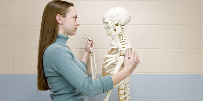 Female student dancing with human skeleton
