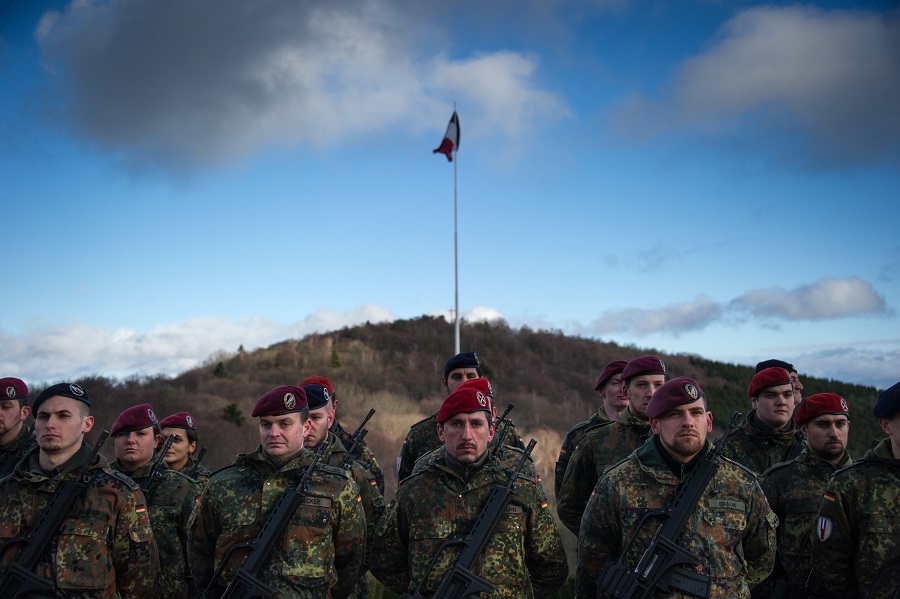 Soldiers of the German armed forces Bundeswehr stand in front of a French national flag as they attend a centenary commemorative ceremony for the Vosges' battle at the World War One Hartmannswillerkopf National Monument, also known as the Vieil Armand, in Wattwiller, eastern France, on December 21, 2015. Throughout 1915, French and Germans fought for control of the mountain peak. 30,000 soldiers died in the battle, with the majority of deaths suffered by the French. / AFP / SEBASTIEN BOZON