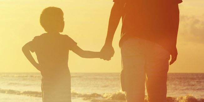 father and son holding hands at sunset sea