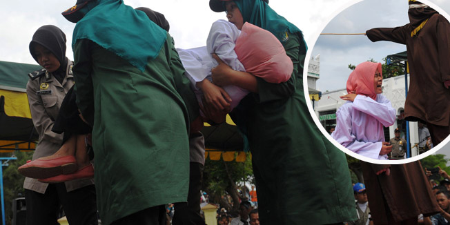 A young Acehnese woman is carried by officials after being caned in public, a punishment under the Islamic sharia law, under the offence of 