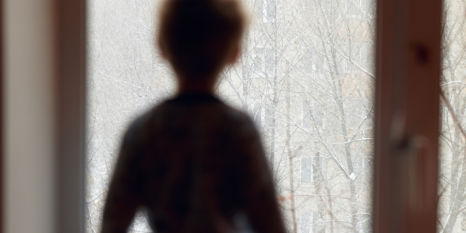 Boy stands on the windowsill and looking through the window.