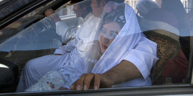 BAMIYAN, AFGHANISTAN - OCTOBER 14:  Afghan bride Zahara, 24, is held by the groom Gulam Ali as they leave for the wedding ceremony in a taxi October 14, 2010 in Bamiyan, Afghanistan. At local beauty salons, behind drawn curtains, isolated from the males, Afghan women spend hours getting ready for engagement parties and weddings. In accordance with Afghan culture the men are required to be segregated from the women with the exception of the bride and groom.(Photo by Paula Bronstein /Getty Images)