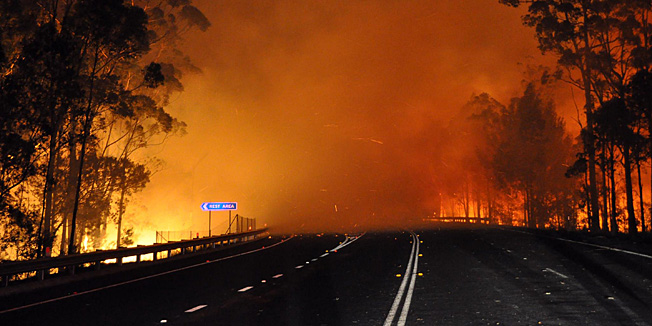 This handout picture taken late on January 8, 2013 and provided by New South Wales Rural Fire Service (NSW Rural Fire Service) on January 9, 2013 shows trees burning and smoke billowing from a fire along the Princes Highway at Deans Gap in the Shoalhaven area in New South Wales. A drop in temperatures helped firefighters battling blazes across Australia on January 9 but up to 30 wildfires were still raging out of control, destroying a handful of homes and forcing people to flee. AFP PHOTO / NSW Rural Fire Service    ----- EDITORS NOTE ---- RESTRICTED TO EDITORIAL USE - MANDATORY CREDIT 