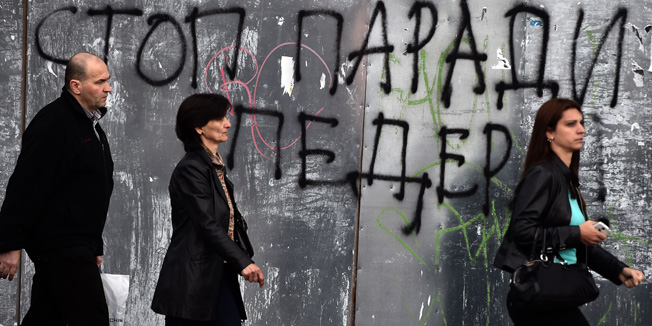 Pedestrian walk past a anti-gay graffiti, reading 