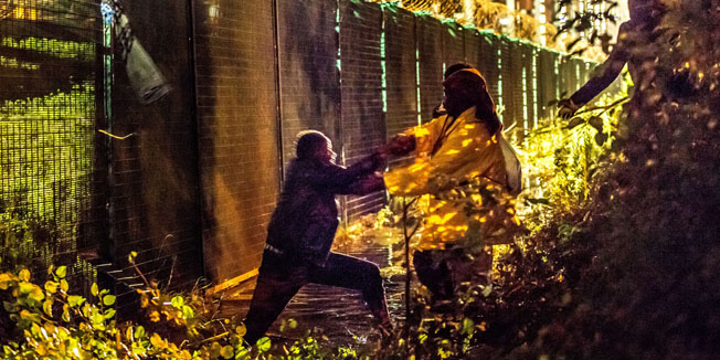 Migrants attempt to the pass the protective fence on the disembarking docks for Eurotunnel shuttles on July 30, 2015 in Coquelles. AFP PHOTO / PHILIPPE HUGUEN