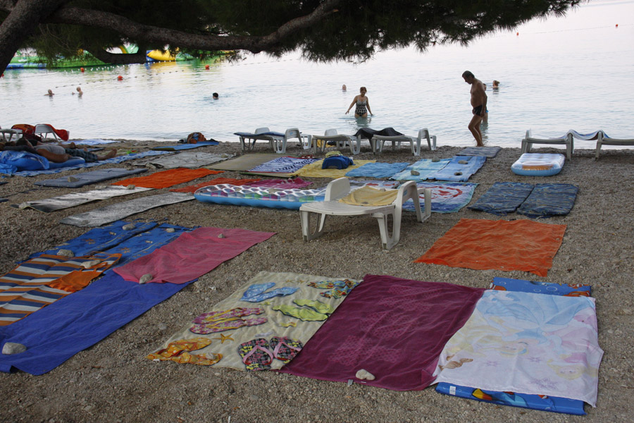 Makarska, 120815.U gradu koji zivi od turizma, a glavni proizvod sto se turistima nudi su sunce i more, mjesto na plazi u jeku sezone je dragocijeno. Tako mnogi turisti ustaju rano i zauzimaju mjesto na zalu prostrtim rucnicima. Situaciju dodatno kompliciraju neki iznajmljivaci lezaljki koji, suprotno gradskim propisima, prekriju svoj dio plaze lezaljkama.   Na fotografiji : Makarska glavna plaza u 7 sati ujutro.Foto: Ivo Ravlic / CROPIX