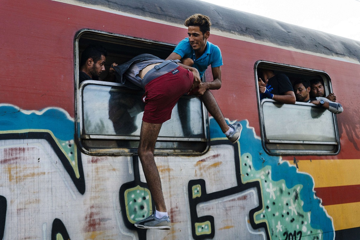 TOPSHOTSA migrant tries to get onto a train heading to the border with Serbia at the train station of Gevgelija, on the Macedonian-Greek border, on August 12, 2015. The EU announced that it has approved 2.4 billion euros ($2.6 billion) of funding to help member states over the next few years cope with the flood of migrants entering the bloc. AFP PHOTO / DIMITAR DILKOFF