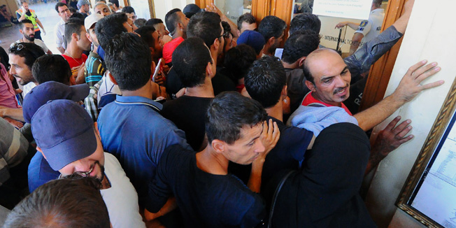 Migrants wait in front of the ticket office of eastern (Keleti) railway station in Budapest on August 31, 2015. The EU is grappling with an unprecedented influx of people fleeing war, repression and poverty in what the bloc has described as its worst refugee crisis in 50 years.  AFP PHOTO / ATTILA KISBENEDEK