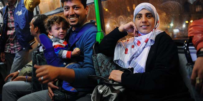 Migrants smile as they wait to depart a transit zone on a public bus to the Hungarian border village Hegyeshalom early in the morning in Budapest on September 5, 2015. The first buses carrying migrants who have been stranded in the Hungarian capital set off for Austria and Germany early after they agreed to receive thousands of refugees desperate to start new lives in Western Europe. AFP PHOTO/ ATTILA KISBENEDEK
