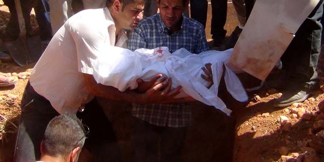 Father of Aylan Kurdi (C), (also know as Aylan Shenu), a three-year-old boy whose drowning off Turkey, holds the body of his child during a funeral ceremony in Kobane, on September 4, 2015. 