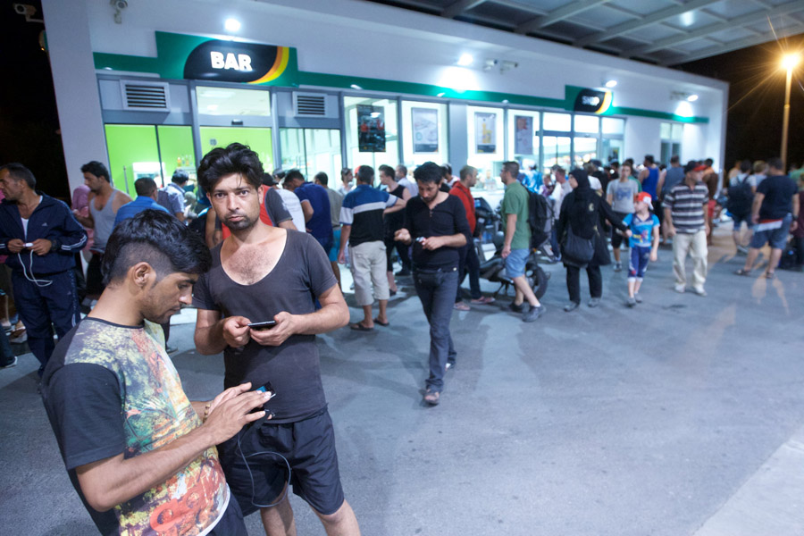 Beli Manastir, 170915.Oko 900 imigranata vlakom je iz Ilace stigo poslije 19 sati u Beli Manastir. Imigrante je policija s kolodvora uputila na nocenje u bivsu vojarnu u kojoj nema struje niti lezaja za imigrante.Na fotografiji: izbjeglice na benzinskoj pumpi u Belom Manastiru.Foto: Vlado Kos / CROPIX