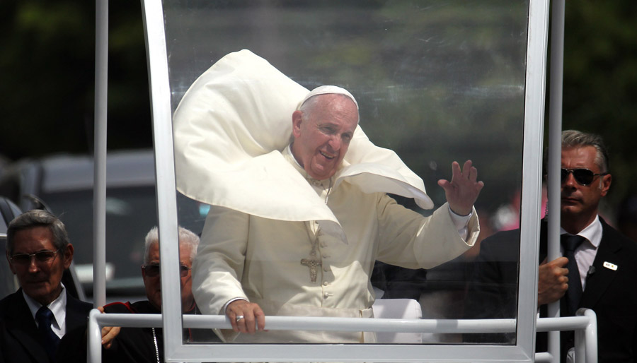 Pope Francis rides through Santiago de Cuba, in eastern Cuba, towards to airport on September 22, 2015. Pope Francis left Cuba Tuesday for his first-ever visit to the United States, where he may get a slightly chillier reception in some quarters than on the Caribbean island. Cuban President Raul Castro saw him off at the airport after a four-day visit that featured three cities, three masses, countless handshakes with adoring crowds, and meetings with both Castro and his big brother Fidel, the men who have ruled the communist island since its 1959 revolution.   AFP PHOTO / POOL / ALEJANDRO ERNESTO