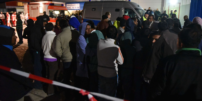 Refugees stand by rescuers and police officers outside a migrants shelter in Calden, near Kassel, on September 27, 2015 where clashes erupted between hundreds of occupants. At least nine people were wounded during the fighting a police spokesman said.  AFP PHOTO / DPA / UWE ZUCCHI +++ GERMANY OUT