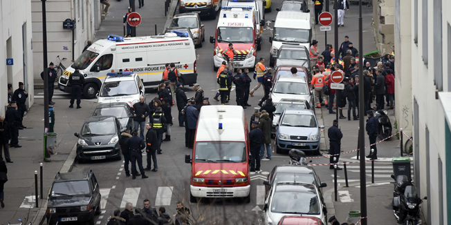 A general view shows firefighters, police officers and forensics gathered in front of the offices of the French satirical newspaper Charlie Hebdo in Paris on January 7, 2015, after armed gunmen stormed the offices leaving twelve dead. Heavily armed gunmen shouting Islamist slogans stormed a Paris satirical newspaper office on January 7 and shot dead at least 12 people in the deadliest attack in France in four decades. Police launched a massive manhunt for the masked attackers who reportedly hijacked a car and sped off, running over a pedestrian and shooting at officers. AFP PHOTO / MARTIN BUREAU