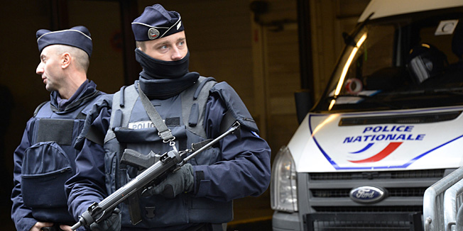 French police officers stand guard in front of the headquarters of French newspaper Liberation as editorial staff of French satirical weekly newspaper Charlie Hebdo and Liberation meet, on January 9, 2015 in Paris, after a deadly attack that occurred on January 7 by armed gunmen on the Paris offices of Charlie Hebdo.  Two brothers suspected of slaughtering 12 people in the attack held one person hostage Friday as police cornered the gunmen northeast of the capital. AFP PHOTO / BERTRAND GUAY