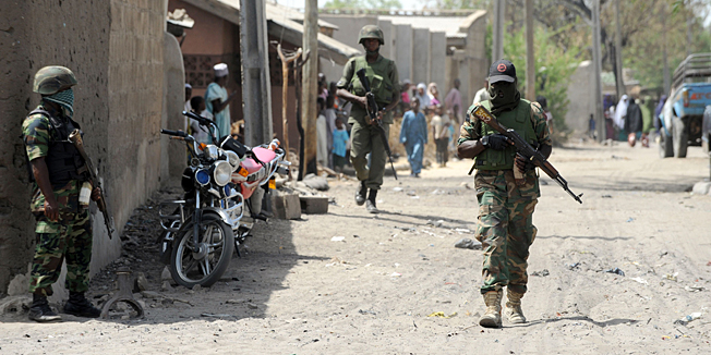 (FILES) -- A file photo taken on April 30, 2013 shows soldiers walking in the street in the remote northeast town of Baga, Borno State. Boko Haram launched renewed attacks around a captured town in restive northeast Nigeria this week, razing at least 16 towns and villages, a local government and a union official told AFP on January 8, 2015. 