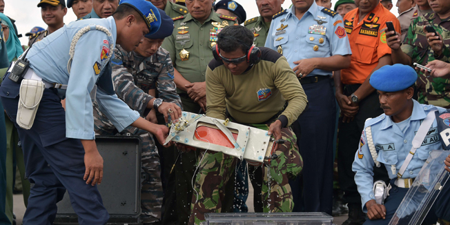 Indonesian officers move the FDR (Flight Data Recorder) (C) of the AirAsia flight QZ8501 into a suitable protective transportation case in Pangkalan Bun after it was retrieved from the Java Sea on January 12, 2015. Indonesian divers on January 12 retrieved the flight data recorder of the AirAsia plane that went down in the Java Sea with 162 people on board, a potential breakthrough in efforts to discover what caused the crash.  AFP PHOTO / ADEK BERRY
