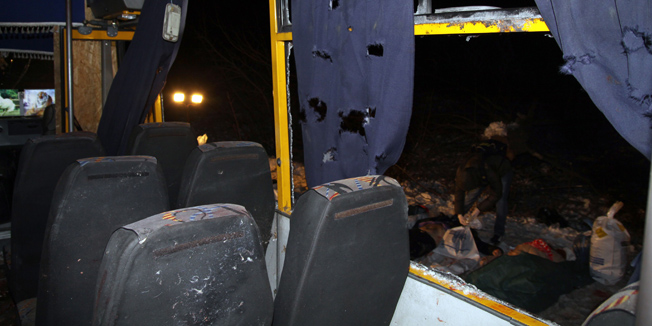 Bodies (R) are laid out next to a damaged bus hit during shelling apparently aimed at a checkpoint manned by Ukrainian forces in Volnovakha, in the eastern Donetsk region, on January 13, 2015. Eleven Ukrainian civilians were killed and nearly 20 injured when a long-range Grad rocket apparently fired by pro-Russian insurgents hit an intercity bus in the separatist east.  Local police said the rocket appeared to have gone astray after being aimed by the gunmen at a checkpoint set up by government soldiers on the main highway connecting the rebel stronghold of Donetsk with Ukraine's southeastern coast on the Sea of Azov. AFP PHOTO/ ALEXANDER  GAYUK
