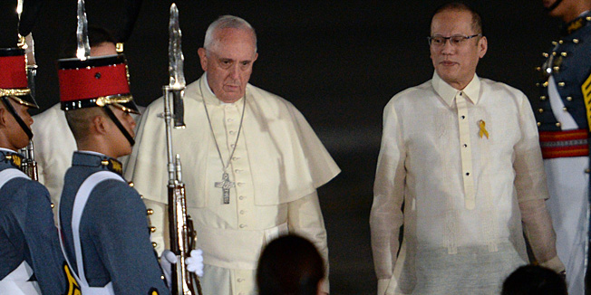 Pope Francis (centre L) walks with Philippine President Benigno Aquino (2nd R) shortly after arriving at a military airbase in Manila on January 15, 2015. Pope Francis will immerse himself January 15 in the Catholic Church's passionate and chaotic Asian heartland as he lands in the Philippines for a five-day trip that is tipped to attract a world-record papal crowd.   AFP PHOTO/TED ALJIBE