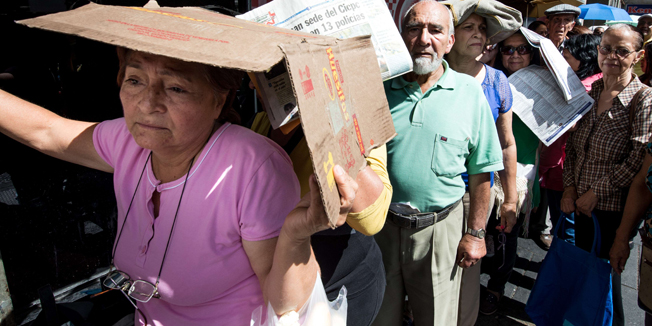 People queue up outside a supermarket in Caracas on January 15, 2015. Venezuela suffers from shortages of nearly a third of all basic goods, inflation that ballooned to 64 percent in 2014 and a recession triggered in part by a scarcity of hard currency that limits imports of essential goods. AFP PHOTO/FEDERICO PARRA