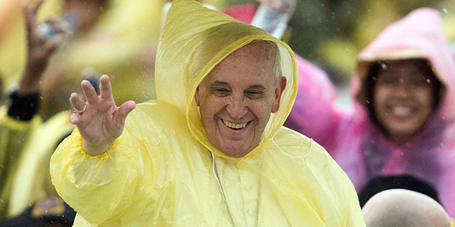 Pope Francis, wearing a plastic poncho, waves to well-wishers after a mass in Tacloban on January 17, 2015. Pope Francis braved heavy rain on January 17 to celebrate an emotional mass with a sea of weeping survivors of a super typhoon in the Philippines that killed thousands, saying their pain silenced his heart.     AFP PHOTO / JOHANNES EISELE
