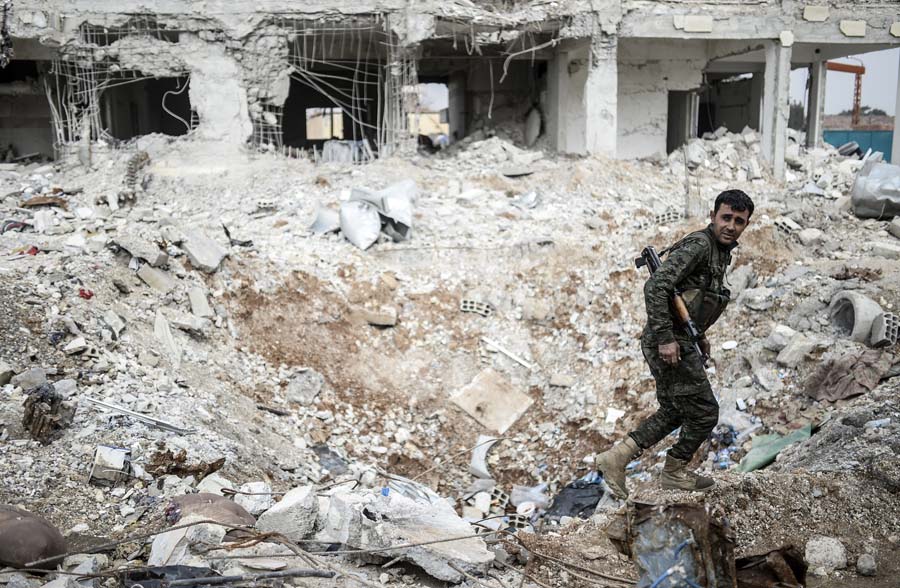 TOPSHOTSA Kurdish fighter walks through the wreckage of a building in the center of the Syrian town of Kobane, also known as Ain al-Arab, on January 28, 2015. Kurdish forces recaptured the strategic town on the Turkish frontier on January 26 in a symbolic blow for the jihadists who have seized swathes of territory in a brutal onslaught across Syria and Iraq. AFP PHOTO / BULENT KILIC