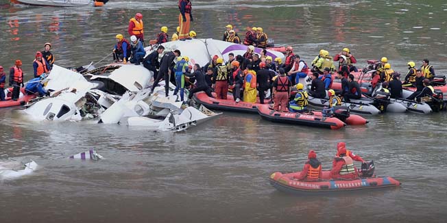 (FILES) This file photo February 4, 2015 shows rescue personnel searching for passengers from the wreckage of a TransAsia ATR 72-600 turboprop plane that crash-landed into the Keelung river outside Taiwan's capital Taipei in New Taipei City. Taiwan's TransAsia Airways announced on February 11, 2015 that it would pay nearly half a million USD in compensation to relatives of each of the victims of a dramatic plane crash earlier this month.         AFP PHOTO / FILES / SAM YEH