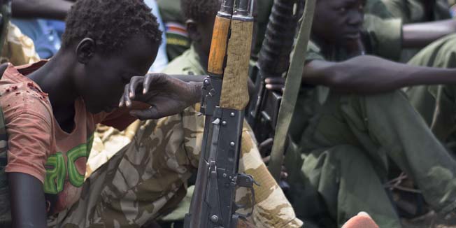 Young boys, children soldiers sit on February 10, 2015 with their rifles at a ceremony of the child soldiers disarmament, demobilisation and reintegration in Pibor oversawn by UNICEF and partners. UNICEF and its partners have overseen the release of another 300 children from the Cobra Faction armed group of former rebels of David Yau Yau. The children in Pibor, Jonglei State, surrendered their weapons and uniforms in a ceremony overseen by the South Sudan National Disarmament, Demobilization and Reintegration Commission, and the Cobra Faction and supported by UNICEF. They were to spend their first night in an interim care center where they will be provided with food, water and clothing. They will also have access to health and psychosocial services. AFP PHOTO/Charles LOMODONG