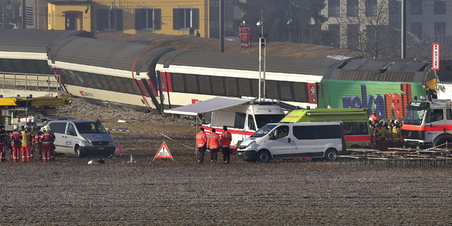 Rescue workers inspect the site of a train crash at the train station of Rafz, northern Switzerland, on February 20, 2015. Two trains slammed into each other north of the Swiss city of Zurich at the start of rush hour, leaving dozens of passengers injured and train carriages upturned, police and media said. AFP PHOTO / MICHAEL BUHOLZER