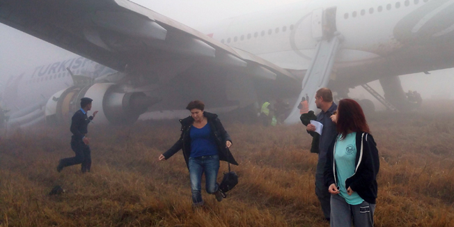Passengers walk away from a Turkish Airlines plane after it skidded off the runway while landing at Kathmandu airport in the Nepalese capital Kathmandu on March 4, 2015. Aviation officials said no one on board was injured, although one witness described how terrified passengers leapt from their seats as the cabin filled with smoke after the plane skidded to a halt. AFP PHOTO / Dikesh Malhotra