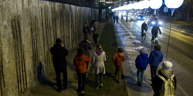 People walk past the light installation Lichtgrenze (Light border) on the course of the former Berlin wall in Berlin on November 7, 2014. Germany kicked off celebrations of the 25th anniversary of the epochal fall of the Berlin Wall Friday, set to culminate in rock stars and freedom icons joining millions at an open-air party. AFP PHOTO / JOHN MACDOUGALL