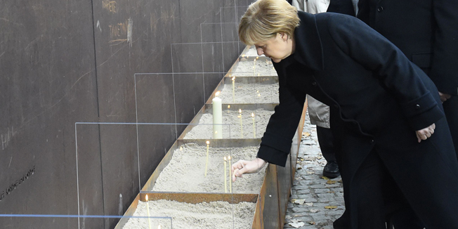 German Chancellor Angela Merkel (L) and Berlin Mayor Klaus Wowereit (R) light candles at the National Memorial for the Victims of the Berlin Wall during the commemorations to mark the 25th anniversary of the fall of the Berlin Wall at the Berlin Wall Memorial in the Bernauer Strasse in Berlin, on November 9, 2014.  AFP PHOTO / TOBIAS SCHWARZ